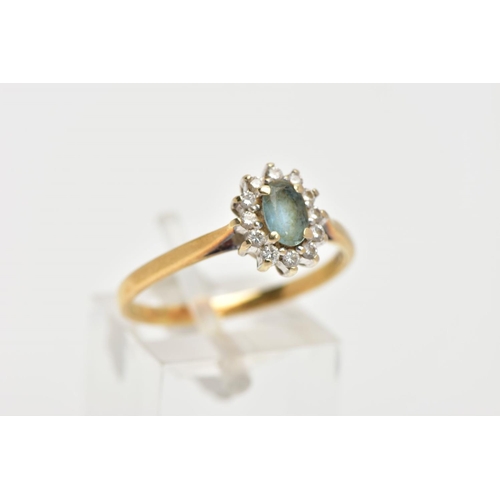 146 - AN 18CT GOLD GEM SET CLUSTER RING, of an oval form, centring on an oval cut aquamarine, within a sur... 