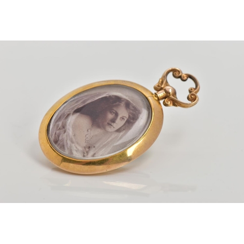 151 - A 9CT GOLD PHOTO PENDANT, an oval pendant fitted with a scroll detail screw bail, a colour photograp... 