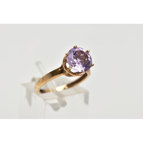 156 - A AMETHYST SOLITAIRE RING, a circular cut amethyst, approximate diameter 9mm, set in a yellow metal ... 