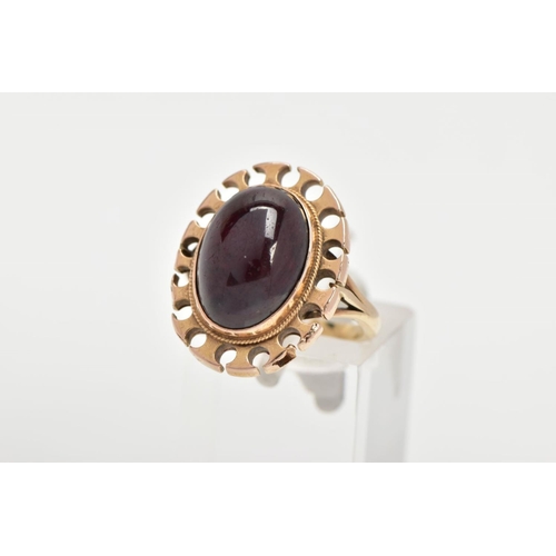 164 - A YELLOW METAL GARNET RING, of an oval form set with an oval garnet cabochon, bezel set with a fine ... 