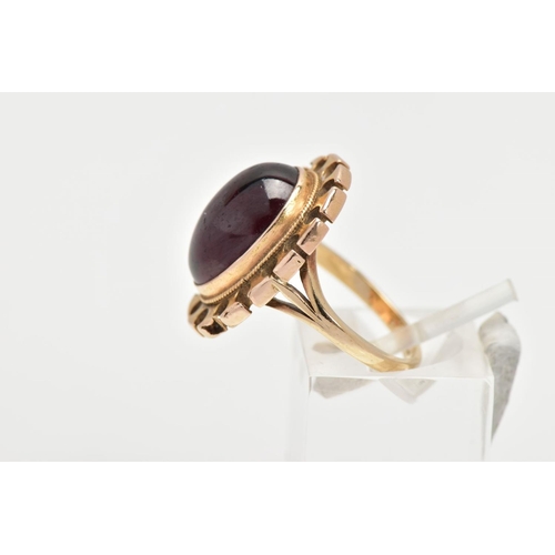 164 - A YELLOW METAL GARNET RING, of an oval form set with an oval garnet cabochon, bezel set with a fine ... 