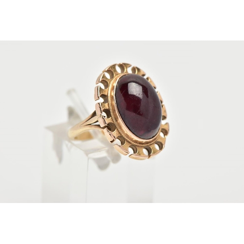 164 - A YELLOW METAL GARNET RING, of an oval form set with an oval garnet cabochon, bezel set with a fine ... 