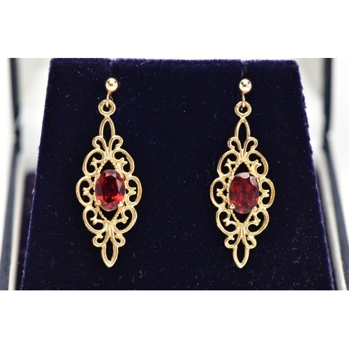 19 - A PAIR OF GARNET EARRINGS, a pair of yellow metal filigree designed drop earrings, set with an oval ... 