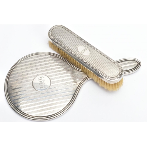 192 - A SILVER VANITY MIRROR AND CLOTHES BRUSH, the mirror of a round form, engine turned design and engra... 