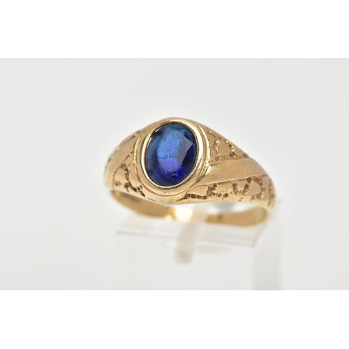 23 - A 9CT GOLD SIGNET RING, of an oval design, set with an oval cut blue stone assessed as paste, textur... 