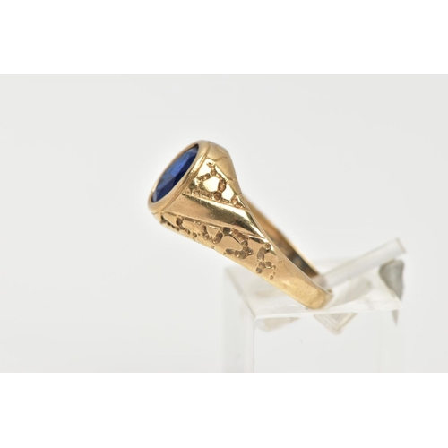 23 - A 9CT GOLD SIGNET RING, of an oval design, set with an oval cut blue stone assessed as paste, textur... 