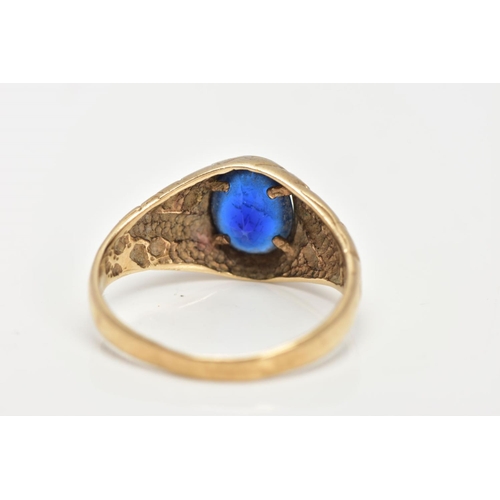 23 - A 9CT GOLD SIGNET RING, of an oval design, set with an oval cut blue stone assessed as paste, textur... 