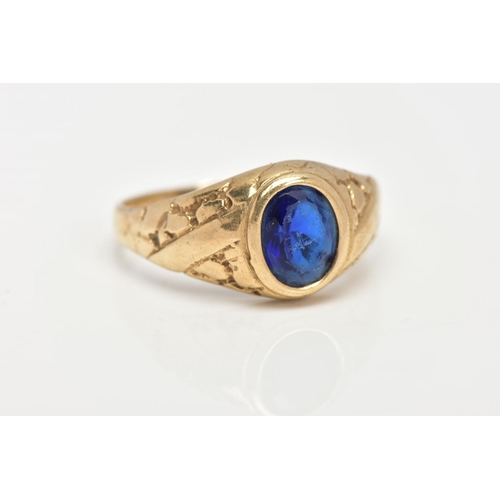 23 - A 9CT GOLD SIGNET RING, of an oval design, set with an oval cut blue stone assessed as paste, textur... 