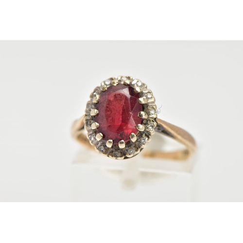 25 - A GARNET AND DIAMOND CLUSTER RING, an oval cut almandine garnet surrounded with a halo of round bril... 