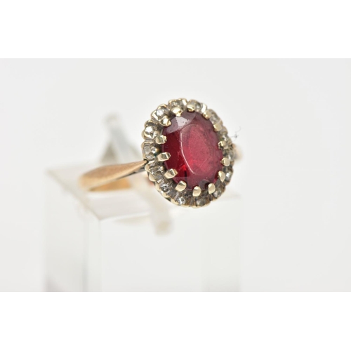 25 - A GARNET AND DIAMOND CLUSTER RING, an oval cut almandine garnet surrounded with a halo of round bril... 