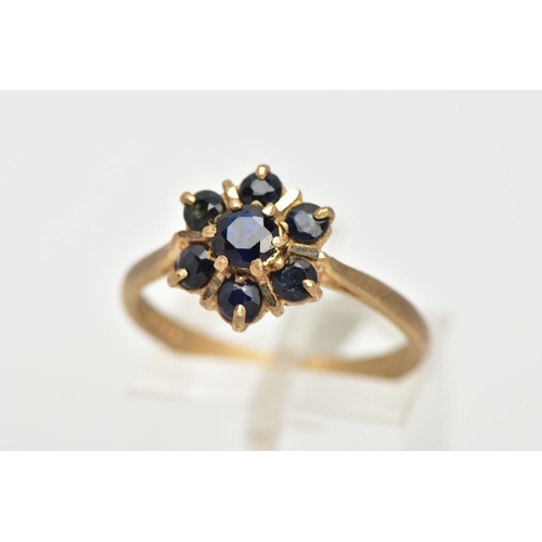 27 - A 9CT GOLD SAPPHIRE CLUSTER RING, seven circular cut sapphires prong set in a floral design, leading... 