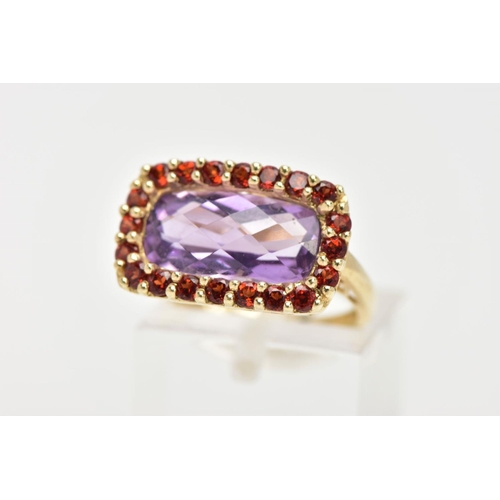 29 - AN AMETHYST AND GARNET DRESS RING, a fancy cut amethyst set with a halo of circular cut garnet stone... 