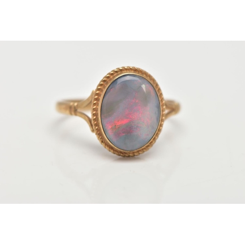 32 - A 9CT GOLD OPAL RING, of an oval design, set with an opal cabochon, displaying blue and red play of ... 