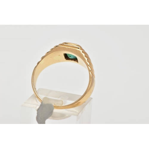 59 - A YELLOW METAL EMERALD SIGNET RING, centring on an emerald cut emerald, bezel set, textured design e... 