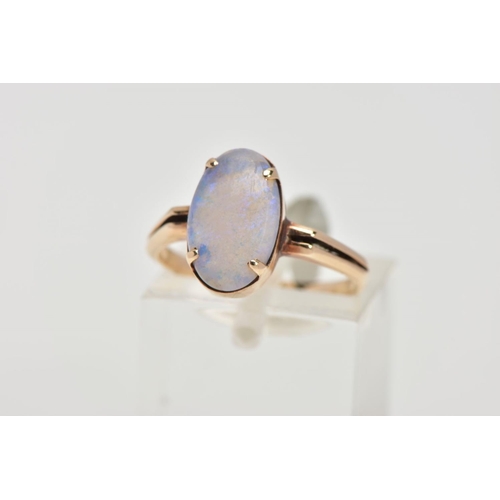 62 - A YELLOW METAL OPAL RING, designed with a four claw set oval opal cabochon, bifurcated shoulders lea... 