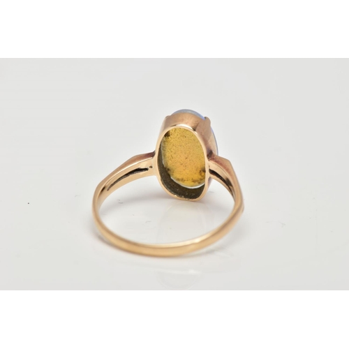 62 - A YELLOW METAL OPAL RING, designed with a four claw set oval opal cabochon, bifurcated shoulders lea... 