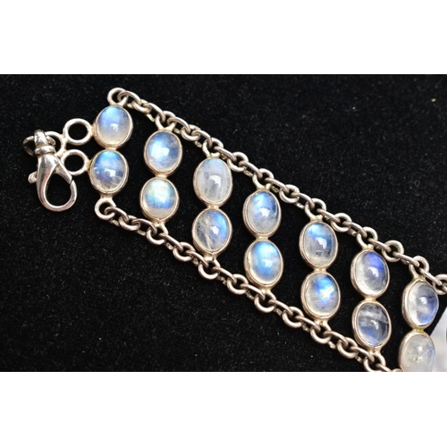 66 - A WHITE METAL MOONSTONE BRACELET, designed with two rows of oval cabochon moonstones each collet mou... 