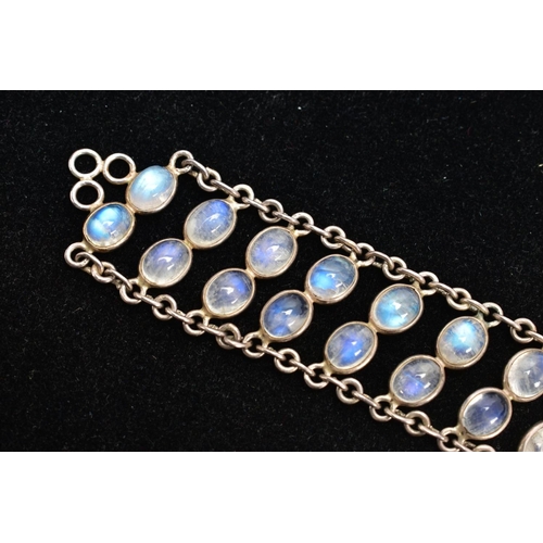 66 - A WHITE METAL MOONSTONE BRACELET, designed with two rows of oval cabochon moonstones each collet mou... 