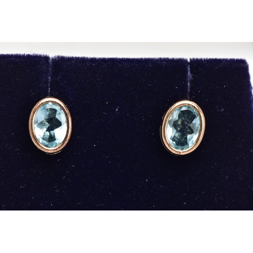 28 - A PAIR OF GEM SET EARRINGS, oval cut blue stones assessed at topaz set in a yellow metal basket sett... 