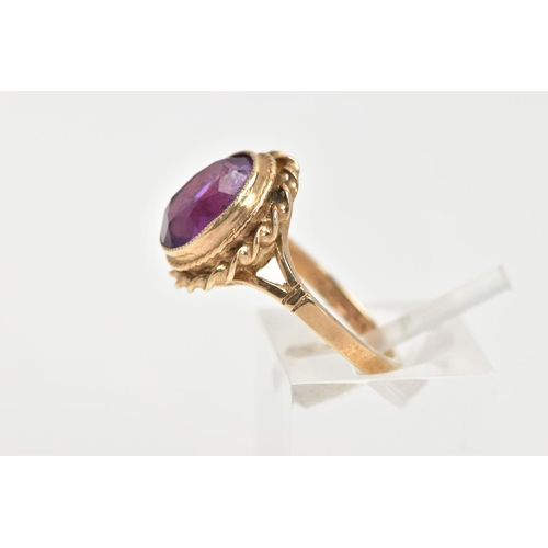 34 - A 9CT GOLD AMETHYST DRESS RING, an oval cut amethyst set in a yellow gold bezel setting and a rope t... 