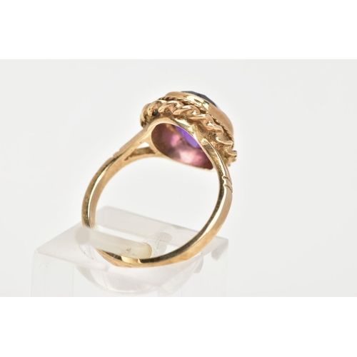 34 - A 9CT GOLD AMETHYST DRESS RING, an oval cut amethyst set in a yellow gold bezel setting and a rope t... 