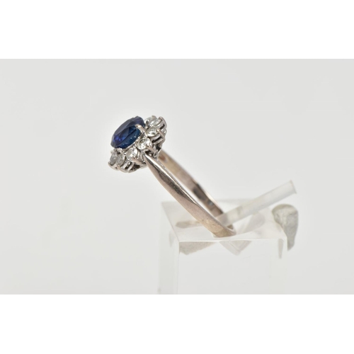 48 - A SAPPHIRE AND DIAMOND CLUSTER RING, centring on a four claw set, oval cut blue sapphire, within a s... 