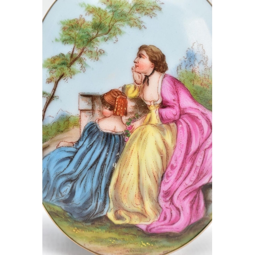 63 - A LARGE PAINTED CERAMIC BROOCH, painted scene depicting two lady's in dresses sitting on a wall with... 