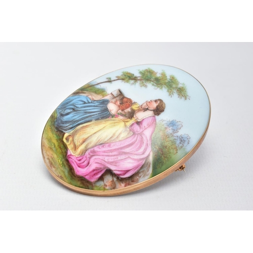 63 - A LARGE PAINTED CERAMIC BROOCH, painted scene depicting two lady's in dresses sitting on a wall with... 