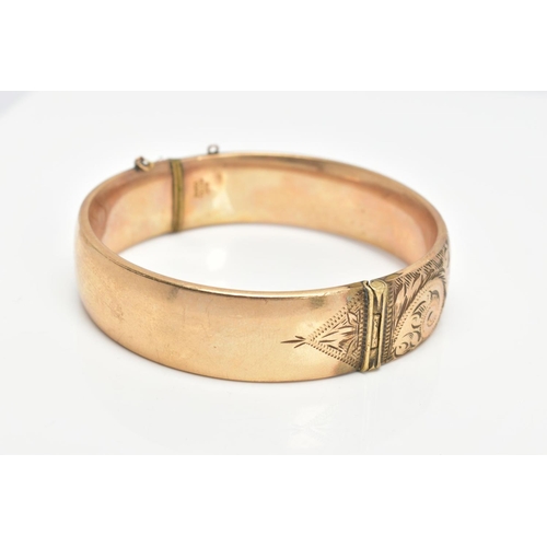 64 - A 9CT GOLD METAL CORE BANGLE, half with a foliate scroll detail, fitted with a push pin clasp, missi... 