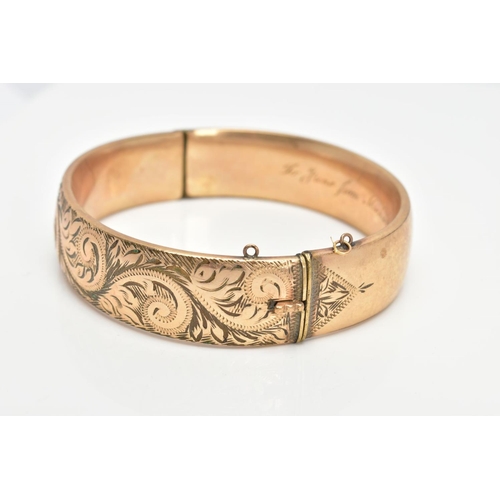 64 - A 9CT GOLD METAL CORE BANGLE, half with a foliate scroll detail, fitted with a push pin clasp, missi... 