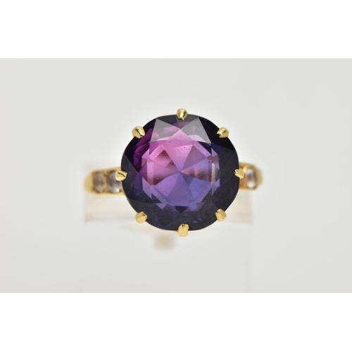 67 - A YELLOW METAL SYNTHETIC SAPPHIRE RING, designed with a circular cut synthetic colour change sapphir... 