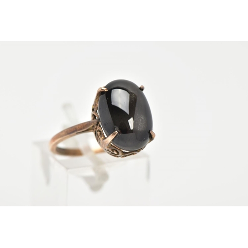 7 - A YELLOW METAL STAR SAPPHIRE DRESS RING, an oval cut black star sapphire cabochon, approximate dimen... 