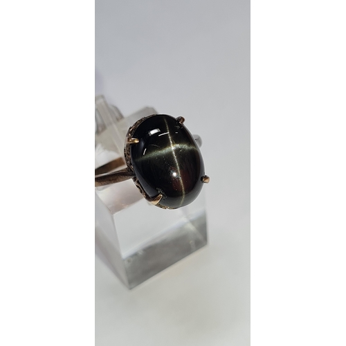 7 - A YELLOW METAL STAR SAPPHIRE DRESS RING, an oval cut black star sapphire cabochon, approximate dimen... 