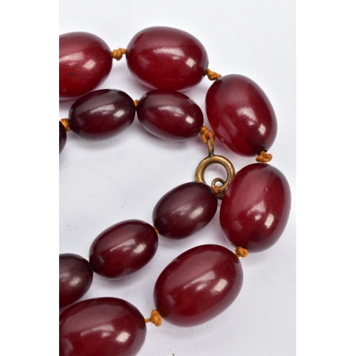 103 - A CHERRY AMBER BAKELITE BEAD NECKLACE, a single row of graduated oval beads, largest measuring appro... 