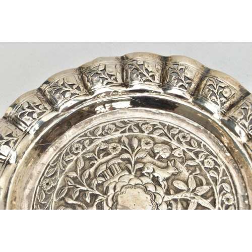 188 - AN INDIAN WHITE METAL TRAY, of a circular form, decorated to the centre with an embossed forest scen... 