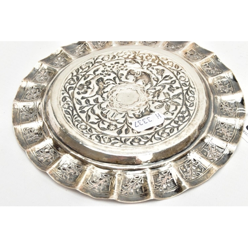 188 - AN INDIAN WHITE METAL TRAY, of a circular form, decorated to the centre with an embossed forest scen... 