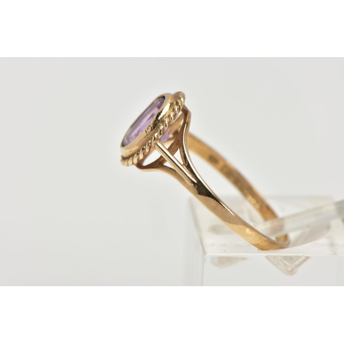 44 - A 9CT GOLD AMETHYST RING, designed with an oval cut amethyst bezel set within a rope twist surround,... 