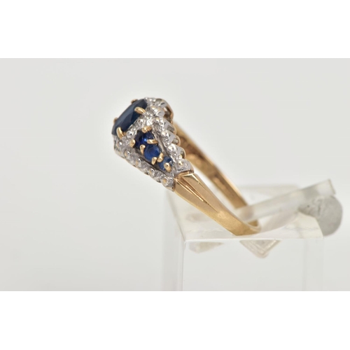 59 - A 9CT GOLD SAPPHIRE RING, designed with a central four claw set, oval cut blue sapphire, flanked wit... 