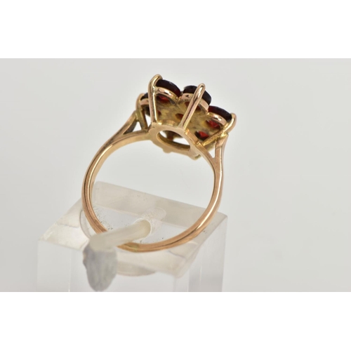 61 - A YELLOW METAL GARNET CLUSTER RING, in the form of a flower cluster, set with seven circular cut gar... 