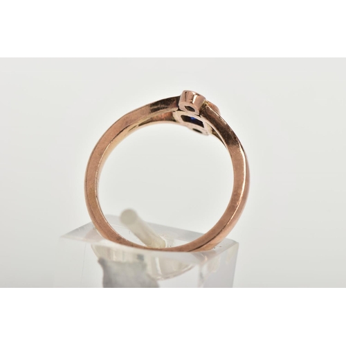 116 - A THREE STONE RING, three graduated circular cut blue stones, within a rose gold tone mount, bifurca... 