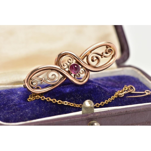 175 - A VICTORIAN GOLD BROOCH, scrolled open work detailing with a central bezel set circular cut ruby, ap... 