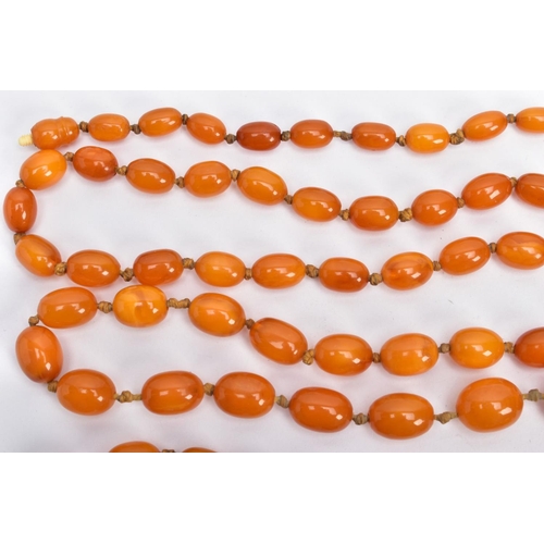 202 - A BUTTERSCOTCH IMITATION AMBER NECKLACE, graduating in size oval beads, fitted to a long double knot... 