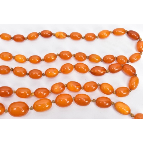 202 - A BUTTERSCOTCH IMITATION AMBER NECKLACE, graduating in size oval beads, fitted to a long double knot... 