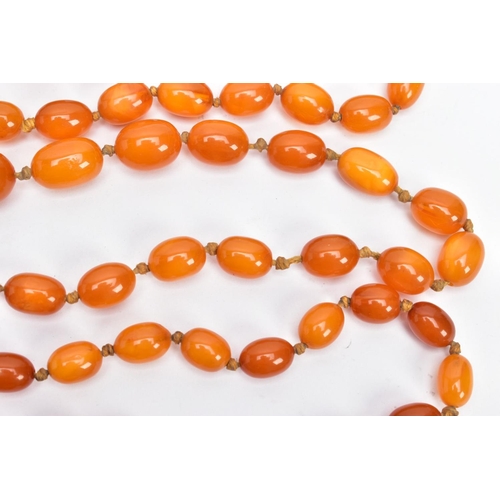 202 - A BUTTERSCOTCH IMITATION AMBER NECKLACE, graduating in size oval beads, fitted to a long double knot... 