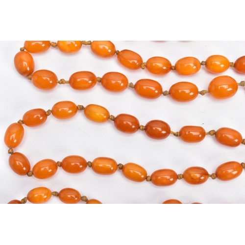 202 - A BUTTERSCOTCH IMITATION AMBER NECKLACE, graduating in size oval beads, fitted to a long double knot... 