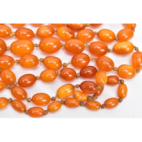 202 - A BUTTERSCOTCH IMITATION AMBER NECKLACE, graduating in size oval beads, fitted to a long double knot... 