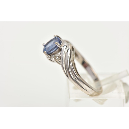 228 - AN 18CT WHITE GOLD RING, designed with a central four claw set, oval cut light blue stone, flanked w... 