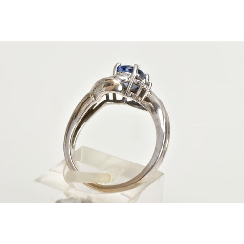 228 - AN 18CT WHITE GOLD RING, designed with a central four claw set, oval cut light blue stone, flanked w... 