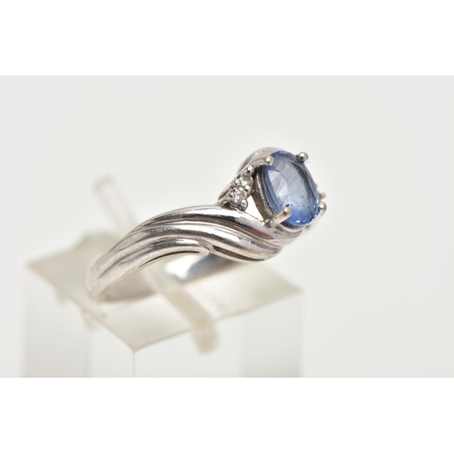 228 - AN 18CT WHITE GOLD RING, designed with a central four claw set, oval cut light blue stone, flanked w... 