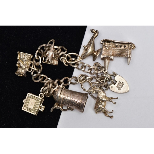 29 - A SILVER CHARM BRACELET, fancy curb link chain, fitted with seven charms in forms such as a church, ... 